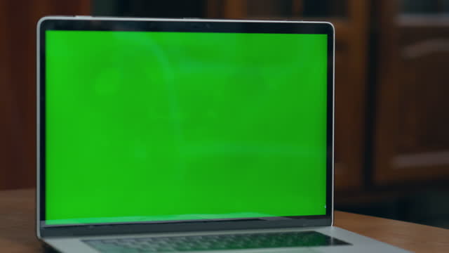 Woman hand turn on green mock-up screen on modern laptop indoor close up.