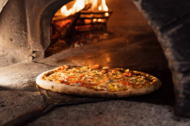 istock Preparing traditional italian pizza in a professional oven with open fire 1488761816