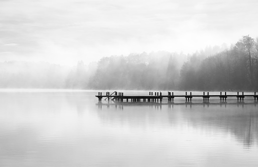 Landscape with a jetty at the lake. Nature with fog in the morning.