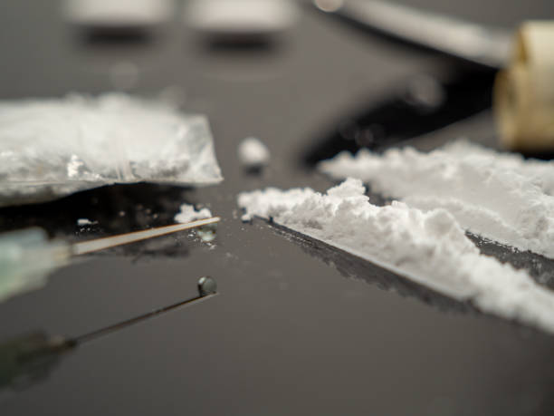 istock Syringe for injection and cocaine powder, on a black background. 1488766107