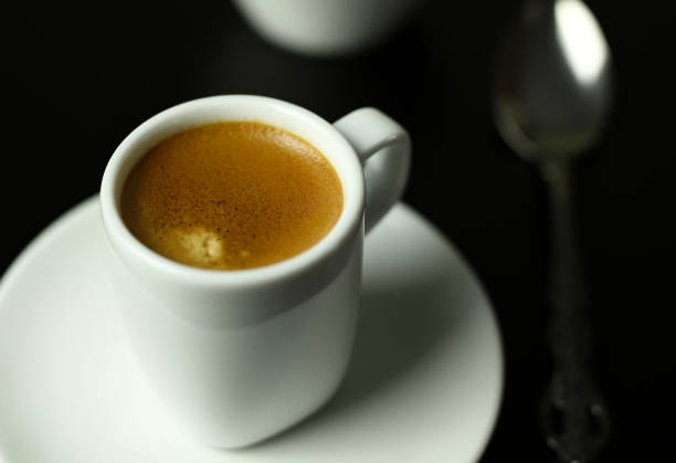 Concept of Italian drink. White cup of classic espresso on black background.