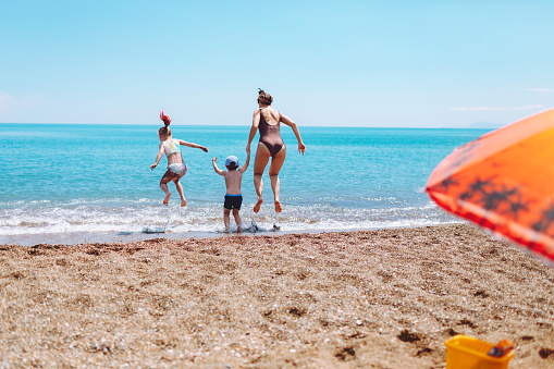 Young adult woman having fun with her daughter and son during sea vacation