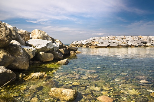 A quiet italian bay with rocks, sand and breakwater barrier - Italy - Tuscany