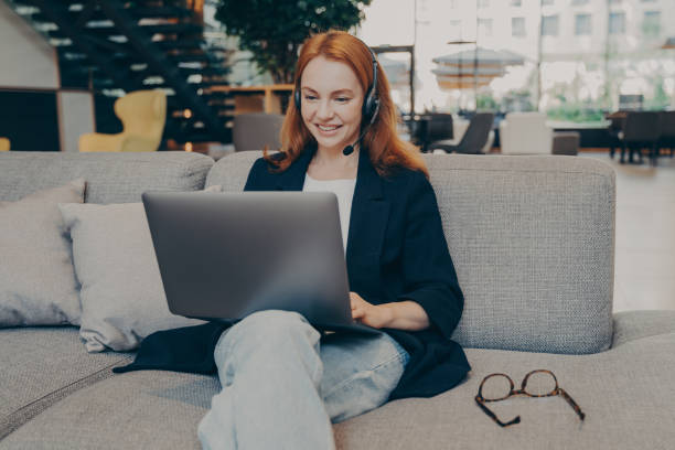 istock Smiling lady freelancer wearing wireless headset, communicating with client via video call on laptop 1488773784