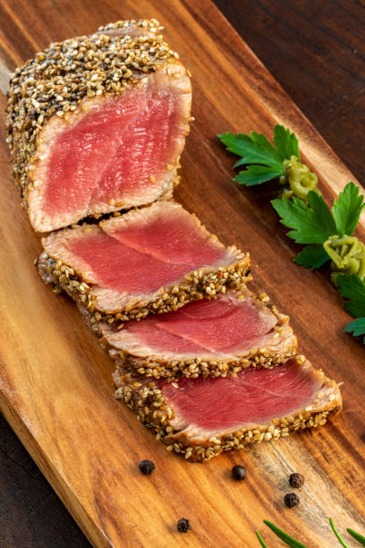 foto vertical de filete de atún aleta amarilla con costra de sésamo sobre tabla de madera - tuna seared tuna steak prepared ahi fotografías e imágenes de stock