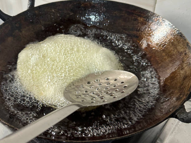 immagine a pieno formato del cibo tradizionale indiano per la colazione, bhatura (bhatoora) frittura profonda in padella di olio bollente, olio da cucina gorgogliante, mestolo di metallo fessurato, vista elevata - photography metal traditional culture full foto e immagini stock