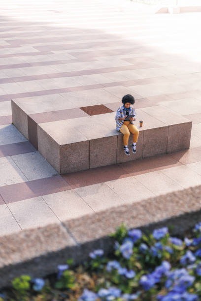 afro dominican woman sat in modern outdoors using tablet, copy space. High quality photo