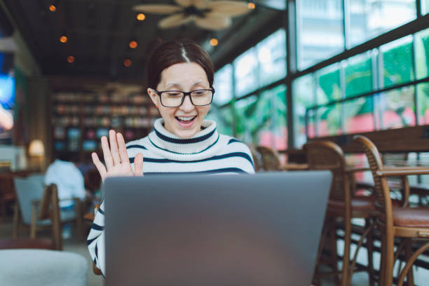 istock Female worker waves hello to coworkers during virtual meeting 1488784887