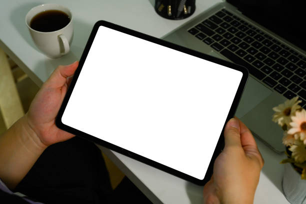 istock Closeup view of worker sitting at white office desk and using digital tablet. Blank screen for advertise text. 1488785368