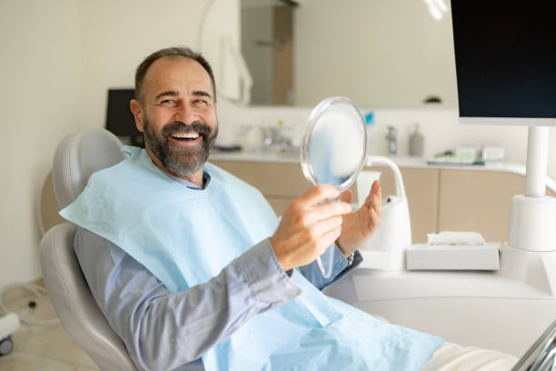 paziente maschio felice che gode dopo lo sbiancamento dei denti dal dentista. - dentist office dentists chair dental equipment white foto e immagini stock