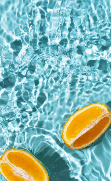 istock Creative summer background with orange fruit slices in swimming pool water. 1488787571