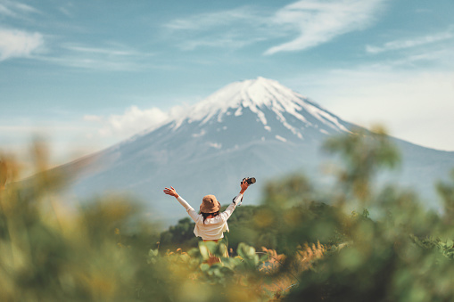 Happy tourist traveler woman enjoying with open arms on lake kawaguchiko with mount fuji in japan, spring and summer, Japan travel vacation