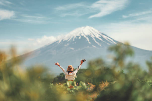 mulher viajante turista feliz desfrutando de braços abertos no lago kawaguchiko com monte fuji no japão, primavera e verão, viagens de férias do japão - beauty one woman only spring beauty in nature - fotografias e filmes do acervo