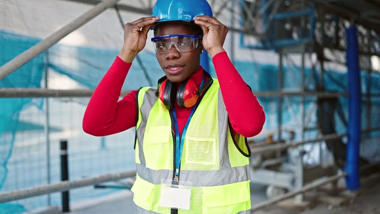 African american woman architect smiling confident wearing hardhat at street