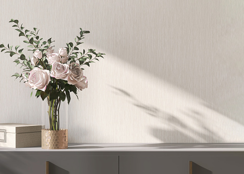 Empty space on modern, minimal gray cabinet, glass vase with pink rose bouquet, gold accessory box in sunlight, shadow on blank beige wallpaper wall for luxury lifestyle, beauty, fashion, interior design decoration, product display background 3D
