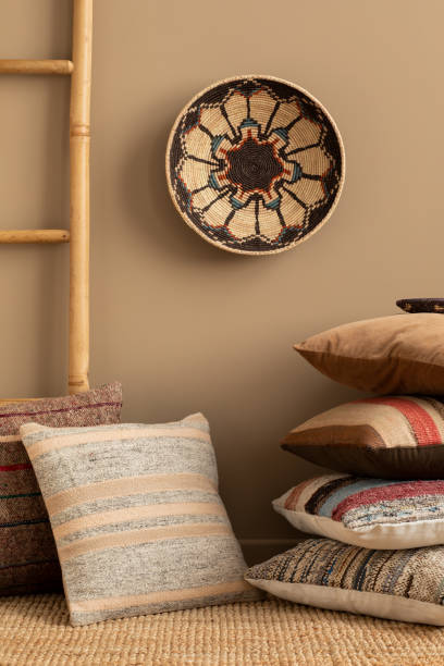 istock Minimalist composition of ethno living room interior with patterned, colorful pillows, brown wall, ladder, braided carpet, round basket on the wall and personal accessories. Home decor. Template. 1488794266