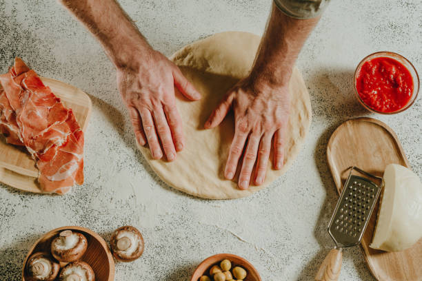 istock Close-up of man preparing pizza on a white table 1488796449