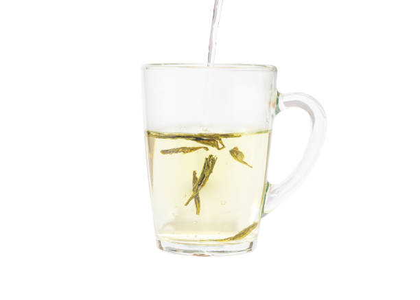 istock Adding hot water to a transparent cup with green tea leaves. 1488799658