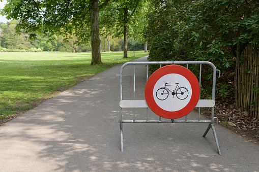 Portable fencing in a park with a warning sign - bicycle access prohibited. Path only for walking