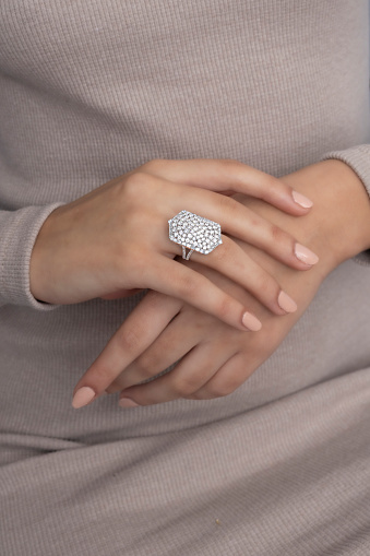 An expensive and embroidered ring made of white gold on the woman's finger. There are precious stones on the ring.