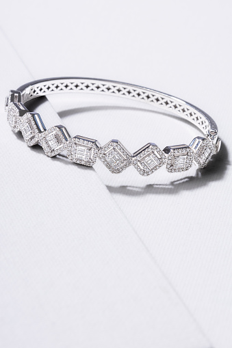 Bracelet made of white gold decorated with precious stones on a white background.