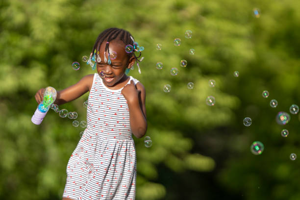 istock A black-skinned girl playing with soap bubbles in the park 1488800368