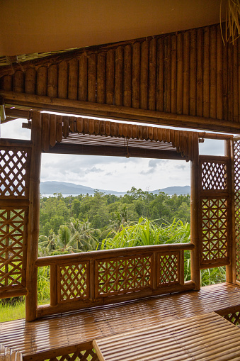 View of a jungle of palm trees on a hill in an Asian island from the patio or porch of a bungalow made in bamboo. Eco lodge or resort mood, tropical vacations.