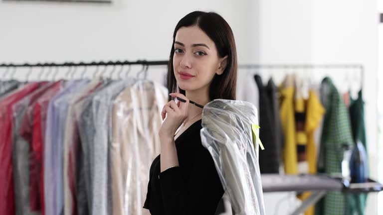 Happy woman holding a clean dry cleaner suit