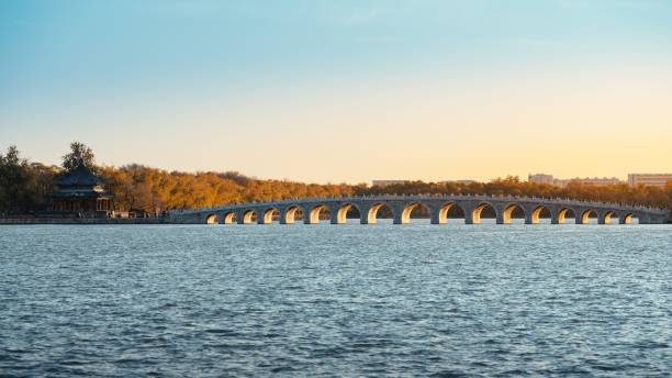istock Picturesque rural scene featuring a bridge crossing a winding river and silhouetted 1488804803