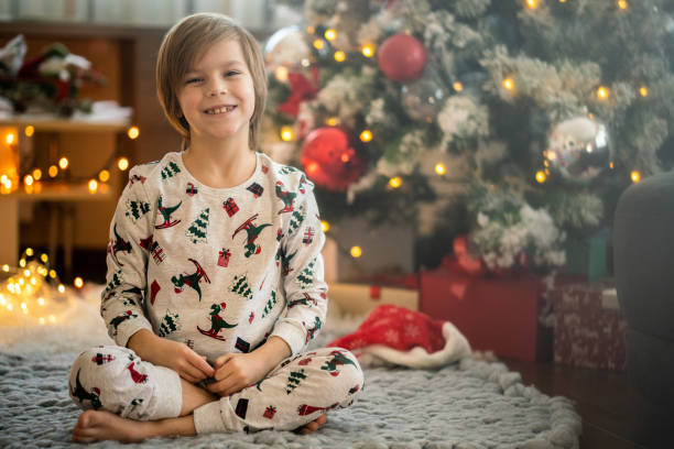 Smiling boy sitting on the floor next to Christmas tree