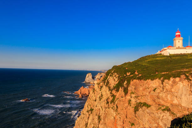 istock Lighthouse on the cliff at Cabo da Roca. Cabo da Roca or Cape Roca is westernmost cape of mainland Portugal, continental Europe and the Eurasian land mass 1488806121
