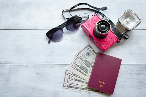 travel concept with retro camera films, money and passport on wood background with copy space