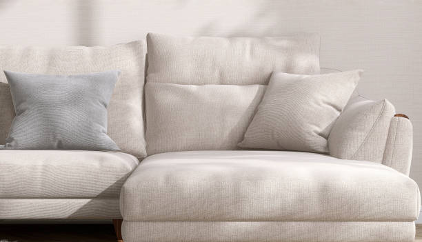 Close up modern, comfortable beige fabric sofa with woven cushion pillow in sunlight on cream fabric texture wallpaper wall