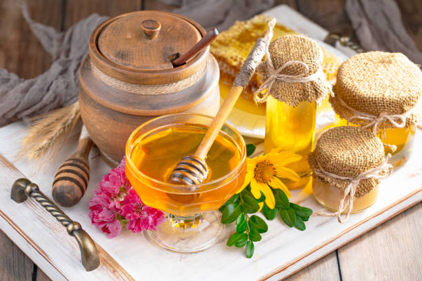 istock Honey in a jar with yellow flowers. 1488815298