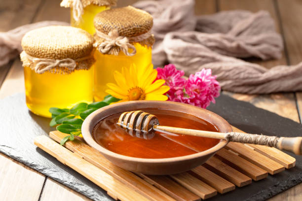 istock Honey in a jar with yellow flowers. 1488815317