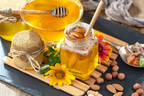 istock Honey in a jar with yellow flowers. 1488815350