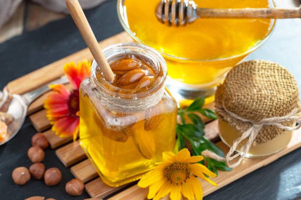 istock Honey in a jar with yellow flowers. 1488815359