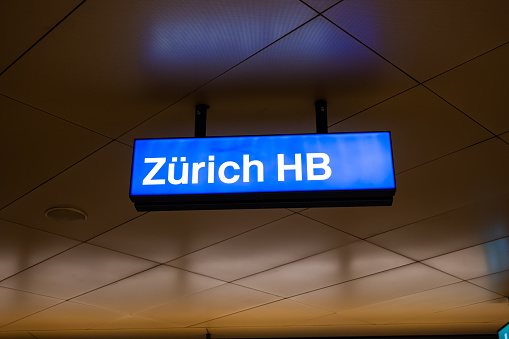 Large blue sign or plaque reading of Zurich or Zürich HB train main station. Low angle view, no people.