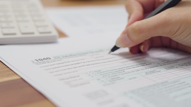 Close up of   woman hands calculates of planning budgets yearly personal finance and fills up the US tax form 1040