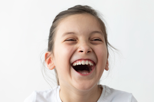 Laughing  little girl in front of white background.