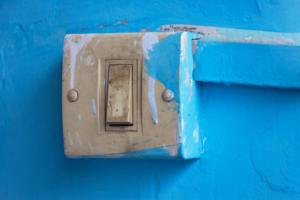 Stock photo showing close-up view of badly painted turquoise wall with paint dripped and smeared over plastic light switch.