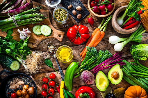 Overhead view of healthy organic vegetables shot on rustic wooden table. The composition includes carrots, broccoli, avocado, corn, beetroot, cucumber,   onion, lettuce, tomato, garlic, bell pepper, radish among others. High resolution 42Mp studio digital capture taken with SONY A7rII and Zeiss Batis 40mm F2.0 CF lens