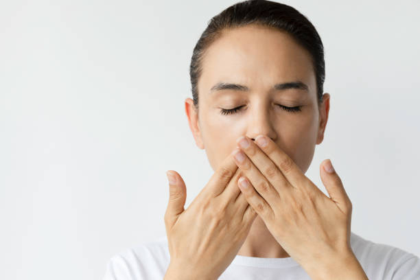 Bad Breath Unrecognizable female is hiding her mouth with her hands because of smell of breath. Halitosis concept closed mouth stock pictures, royalty-free photos & images