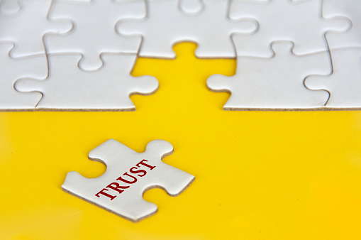 Trust text on missing jigsaw puzzle on yellow background.