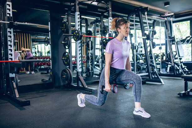 istock Young woman doing squats with dumbbell in gym 1488825101