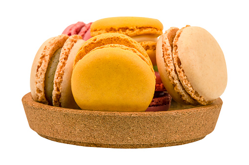 Colorful macaroons in a wooden bowl isolated on white background
