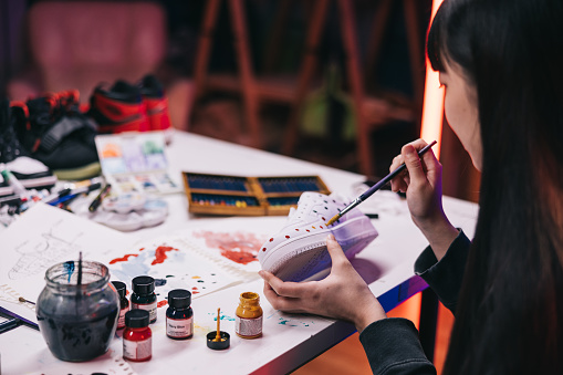 We can see the intricate details of the sneakers taking shape, as the artist uses a steady hand and a keen eye to bring her vision to life.