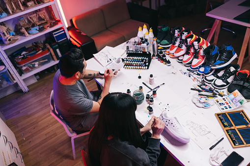 In a bustling studio filled with vibrant energy, two passionate Japanese sneaker artists 
collaborate on a new project, fueled by their shared love of innovative design.