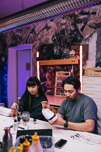 In a bustling studio filled with vibrant energy, two passionate Japanese sneaker artists 
collaborate on a new project, fueled by their shared love of innovative design.