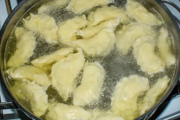 Homemade dumplings cooking in a pot of water in macro close-up